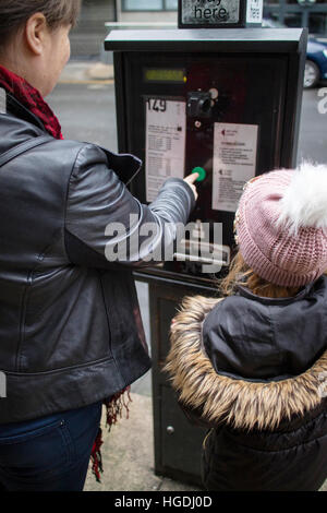 Mother and daughter paying for a car parking ticket from a Parking Pay and Display Ticket Machine Stock Photo