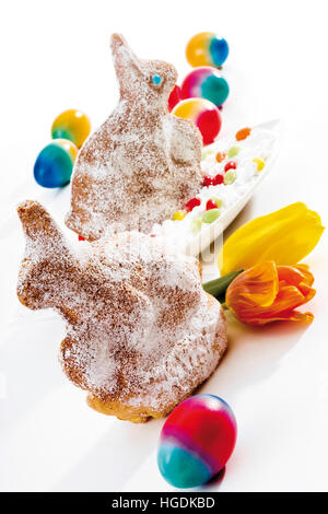 Coloured eggs and Easter bunnies made of sponge cake and covered in icing sugar Stock Photo
