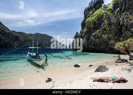 Boat trip tourist tanning on remote beach Bacuit Archipelago Palawan Philippines Stock Photo