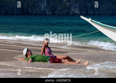 Couple relax on remote beach Bacuit Archipelago Palawan Philippines Stock Photo