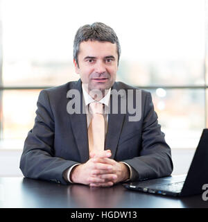 Portrait of senior businessman in office with laptop computer. Stock Photo