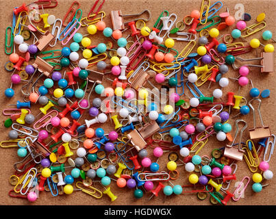 Background of colorful drawing pins, paper clips and metal binder clips on a cork board Stock Photo