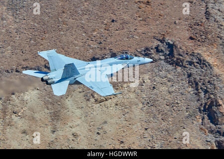 United States Navy F-18-E Flying At Low Level Through A Desert Valley. Stock Photo