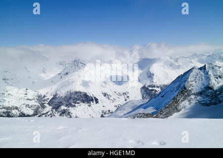Alpine snowy peaks covered by clouds, winter landscape, French Alps Stock Photo