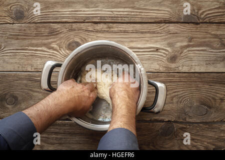 Man makes the dough in the pan on the table horizontal Stock Photo