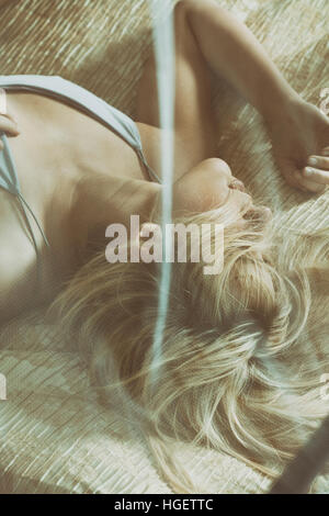 Blond woman laying down in bed Stock Photo
