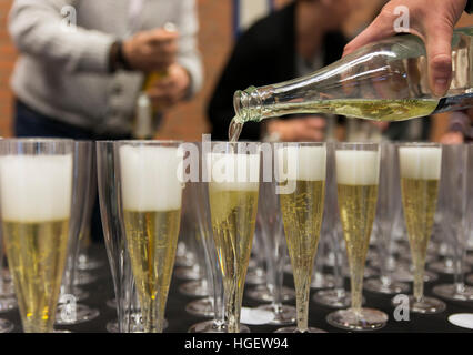 person pouring champagne in a row of glasses during a party for celebration Stock Photo