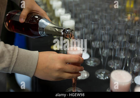 person pouring champagne in a row of glasses during a party for celebration Stock Photo