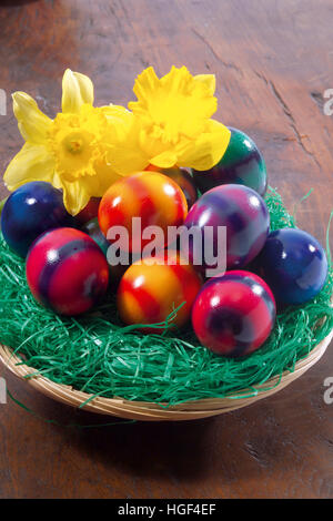 Basket filled with coloured Easter eggs and daffodils Stock Photo