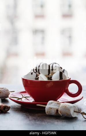 hot chocolate with marshmallows in a red cup near the window Stock Photo
