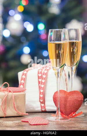 Valentine's Day still life with pair of Champagne flute glasses, gift box and red heart on bokeh background Stock Photo