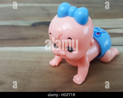 Mechanical wind up crawling baby toy on wood background Stock Photo