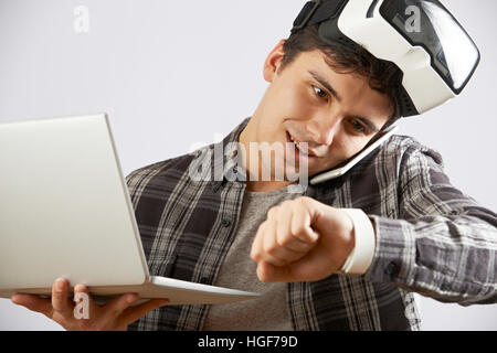 Man In Virtual Reality Headset Looking At Smart Watch And Talking On Mobile Phone Stock Photo