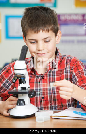 Male Pupil Using Microscope In Science Lesson Stock Photo