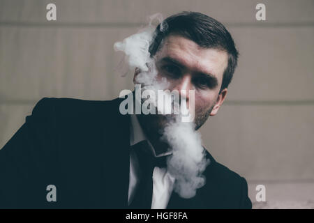 businessman blows smoke from his nose Stock Photo