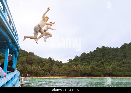 friends jumping to the sea from boat, having fun together, beach tropical adventure, adrenaline Stock Photo