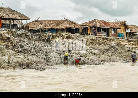 Sunderban, Bangladesh - circa July 2012: Photo of six native men working in mud near their houses and river in Sunderban, Bangladesh. Documentary edit Stock Photo