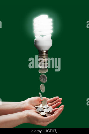 Energy saving lamps helping to save energy and money for family budget, on the green background. Economy of money due to using energy saving lamps. Mo Stock Photo