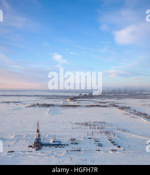 Aerial view of oil rig at an oil field in Western Siberia in the winter day. Gas-jet for gas flaring is located near the rig. Stock Photo