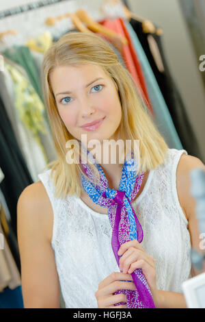 Lady trying on scarf in clothes shop Stock Photo