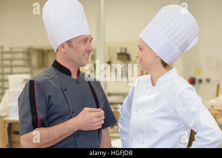 two professionals chefs talking and smiling in the kitchen Stock Photo