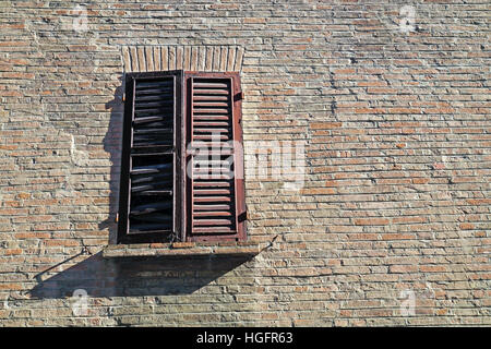 Closed wood window on aged brick wall background. Stock Photo