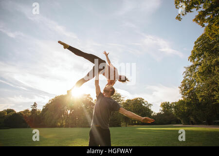 Man lifting woman while doing yoga on sidewalk Stock Photo - Alamy