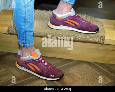 A young man dressed in jeans and sneakers, standing on the stairs. Stock Photo