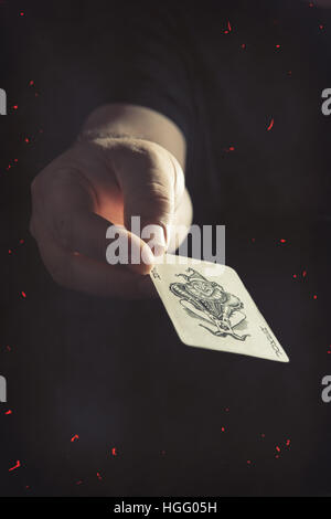 Male hand holding the Joker playing card Stock Photo