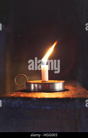 Old wax burning candle in chamberstick Stock Photo
