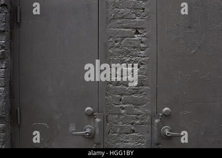 Old gray metal doors and painted bricks wall background Stock Photo