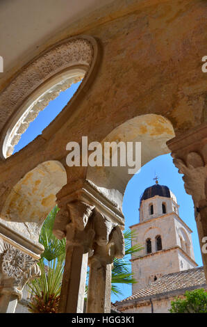 View of  Dubrovnik city bell tower through the arches of the Franciscan monastery situated on the mains street. Stock Photo