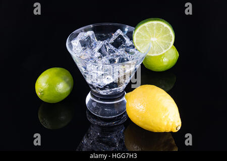 Sparkling beverage in a martini glass with lemons and limes on a black background Stock Photo