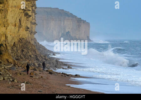 West Bay, Dorset, UK.   9th January 2017.  UK Weather.  Two people on East Beach at West Bay in Dorset watch as large stormy waves crash ashore during the late afternoon, after a day of rain and gusty winds.  Picture: Graham Hunt/Alamy Live News. Stock Photo