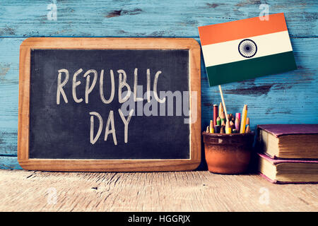 a chalkboard with the text Republic Day written in it and a flag of India, on a rustic wooden surface, against a blue wooden background Stock Photo
