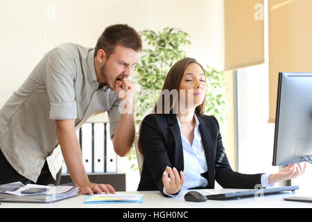 Angry businessman hating to his relaxed colleague at office Stock Photo