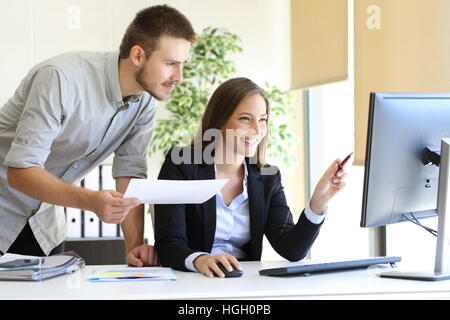 Businesspeople co-working comparing a desktop computer information with paper document at office Stock Photo