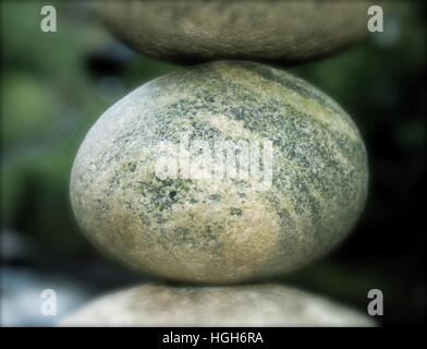 Stuck between a rock and a hard place. River stone suspended between two other stones. Stock Photo