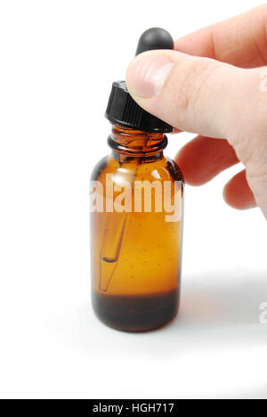 Hand opening a amber eyedropper bottle full of a tincture used for homeopathic medicine or herbal remedies or naturopathy. Stock Photo