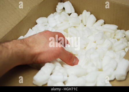 Hand Reaching Into Cornstarch Packing Peanuts - Biodegrabable, environmentally friendly, green, renewable, an environmentally friendly replacement to Stock Photo