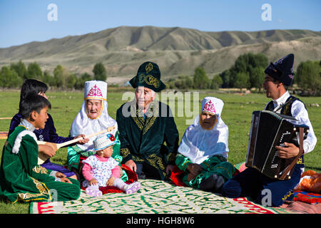 Kazakh family in national costumes sitting in the nature and singing all together. Stock Photo