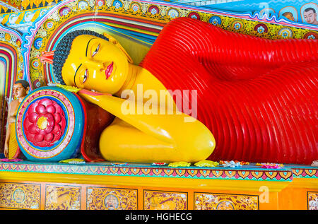 The Reclining Buddha in Isurumuniya Rock Temple, surrounded by painted and carved lotus flowers Stock Photo
