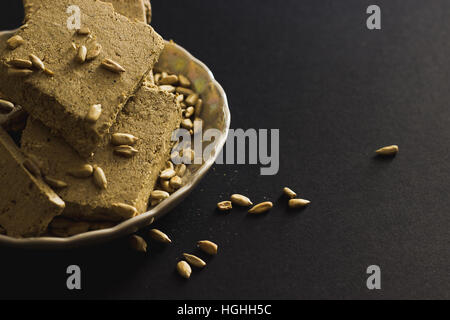 Sunflower halva with seeds on plate, on black background Stock Photo