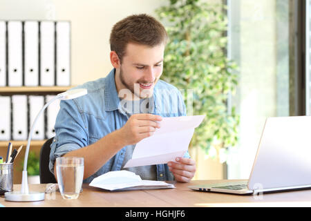 Happy entrepreneur working reading a letter in a desk at office Stock Photo