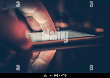 Playing Smartphone in a Dark. Male Finger on the Modern Smartphone Touchscreen Display. Browsing Internet on the Phone. Stock Photo