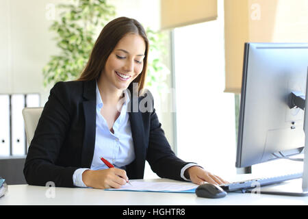 Happy businesswoman signing a contract or document in a desk at office Stock Photo