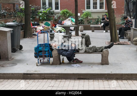 Homeless person sleeping on a bench in China Stock Photo