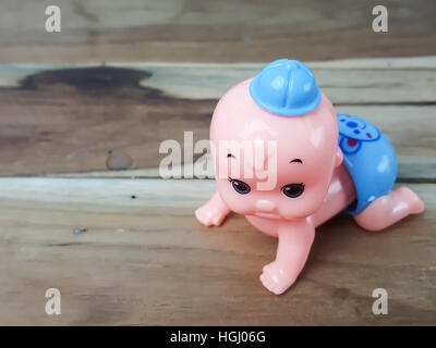 Mechanical wind up crawling baby toy on wood background Stock Photo