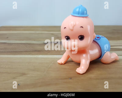 Mechanical wind up crawling baby toy on wood background Stock Photo