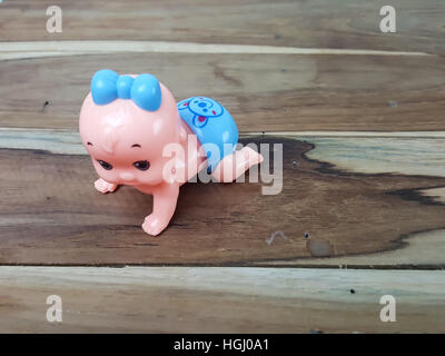 Mechanical wind up crawling baby toy on wood background Stock Photo